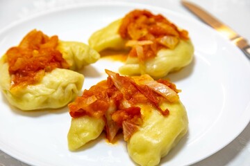 Classic Ukrainian food, perohê or veréneki stuffed with potatoes and cottage cheese and cooked, served with different types of sauce and salted and sour cream