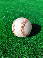 A baseball on a green synthetic field