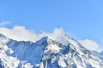 French alps on a sunny day under the clouds by winter covered with snow