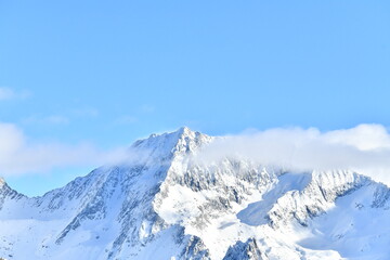 French alps on a sunny day under the clouds by winter covered with snow
