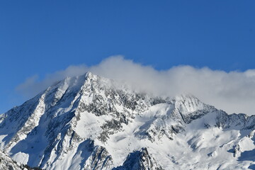 French alps on a sunny day under the clouds by winter covered with snow