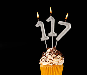 Number 117 shaped candles - Birthday cupcake on black background.