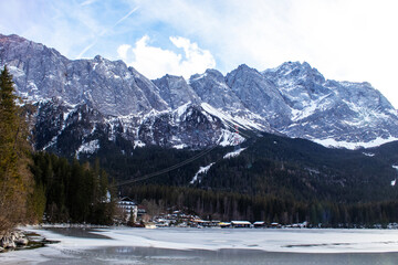 Snow-capped Mountains Rise Above a Frozen Lake in a Serene Winter Landscape With a Distant Cable Car