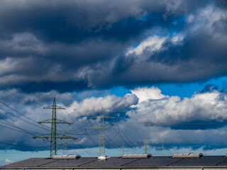 Strommasten einer &Uuml;berlandleitung unter dunklem Wolkenhimmel