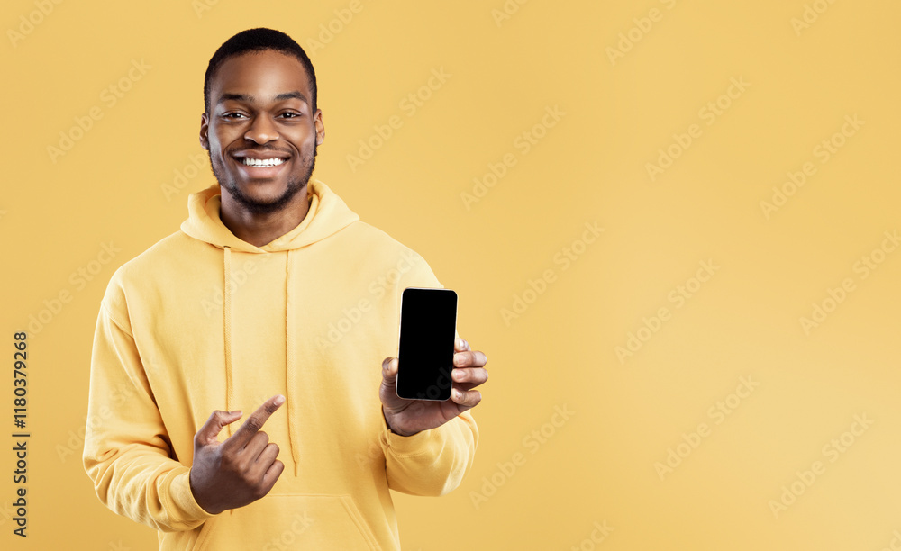 Poster check this mobile application. black man showing phone pointing finger at blank screen smiling to ca