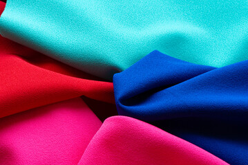 A vibrant arrangement of textured fabrics showcasing bright shades of red, pink, turquoise, and...