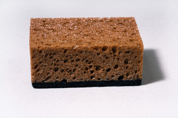 A close-up of a brown sponge featuring a porous texture, showcasing its dark base and soft, absorbent surface.