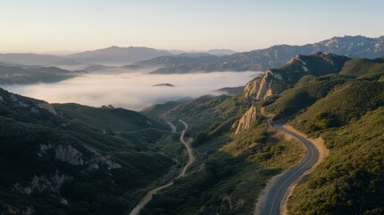Dense fog blankets a rugged mountain terrain, as roads carve through the mist, offering breathtaking views and a sense of mystery.