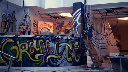Empty abandoned warehouse with graffiti paintings on walls, concept of alternative lifestyle. City slums ghetto location used as crime haven by anti establishment protestors doing street art