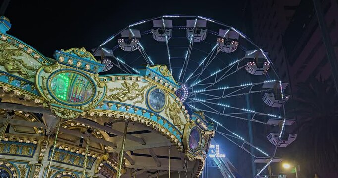 Toma de carrusel con rueda de la fortuna de fondo en la noche