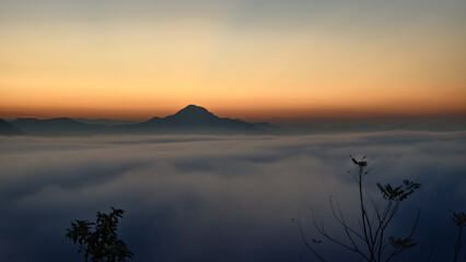 Breathtaking mountain view above clouds at sunset