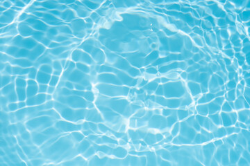 Blue water with ripples on the surface. Defocus blurred transparent blue colored clear calm water surface texture with splashes and bubbles. Water waves with shining pattern texture background.