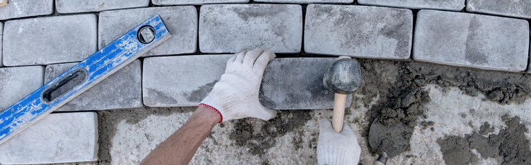 Laying paving stones on cement mortar. Banner. Laying a garden path made of tiles. Self-laying of...