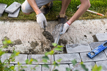 Laying paving stones on cement mortar. Laying a garden path made of tiles. Self-laying of concrete...