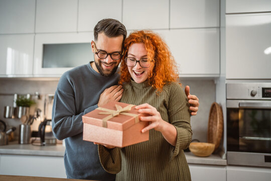 young adult boyfriend surprise her girlfriend with gift box at home