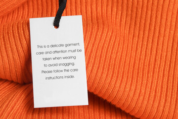 Close up of luxury clothing hang tag. Delicate garment swing tag. Laundry care washing instructions...