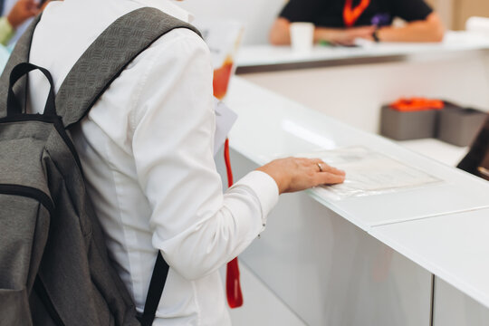 Process of checking in on conference congress forum event, registration desk table, visitors and attendees receiving lanyard with name badge and entry wristband bracelet and register electronic ticket