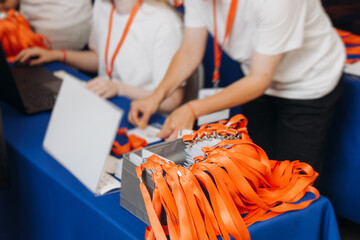 Process of checking in on conference congress forum event, registration desk table, visitors and attendees receiving lanyard with name badge and entry wristband bracelet and register electronic ticket