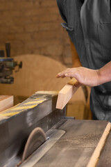 A male carpenter cutting wood with a circular saw in a carpentry sho