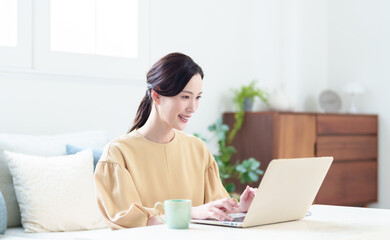 リビングでパソコンを使う女性　リモートワークコンセプト © taka