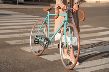 Young woman with bicycle walking across pedestrian crossing