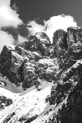 A mountain range covered in snow with a few clouds in the sky