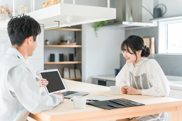 パソコンを使って説明を聞く主婦と説明する作業着姿の営業マンの男性

