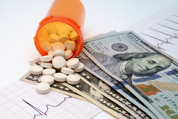 An EKG strip with bottle of pills and cash money on white background