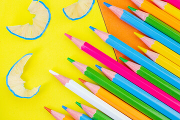 Artistic chaos with colorful pencils and shavings on a bold orange and yellow background.