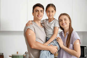 Family with medical patches after vaccination hugging in kitchen