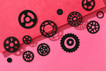 Black paper gears on pink background