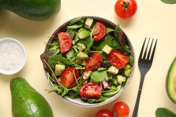 Bowl of tasty avocado salad with cherry tomatoes on yellow background