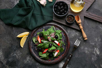 Plate of salad with crab sticks, spinach, black olives and ingredients on grey grunge background © Pixel-Shot