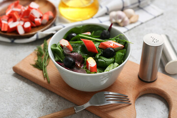 Bowl of salad with crab sticks, spinach and black olives on grey grunge background © Pixel-Shot