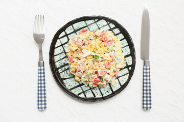 Plate of salad with crab sticks, corn and cucumber on white background