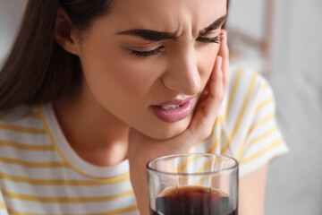 Young woman suffering from toothache with soda at home, closeup