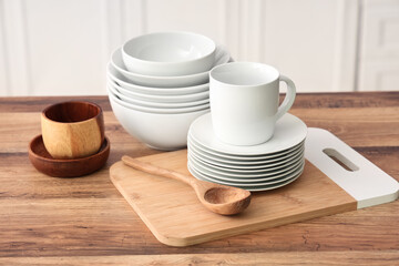 Clean plates, bowls and cutting board on wooden counter in kitchen, closeup