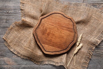 Cutting board, spikelets and burlap fabric napkin on wooden background