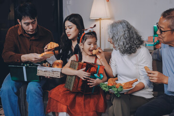 Portrait of Asian family exchanging presents during christmas at home. Attractive happy people holding gift box, celebrate holiday thanksgiving, xmas eve tradition in living room in house together.