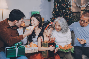 Portrait of Asian family exchanging presents during christmas at home. Attractive happy people holding gift box, celebrate holiday thanksgiving, xmas eve tradition in living room in house together.