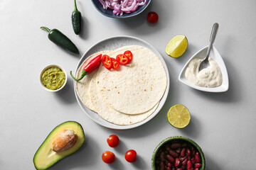 Plate and ingredients for tasty fresh taco on grey background
