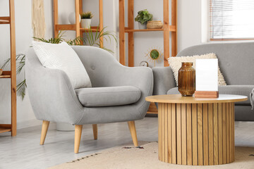 Interior of stylish living room with cozy grey armchair, sofa and wooden coffee table