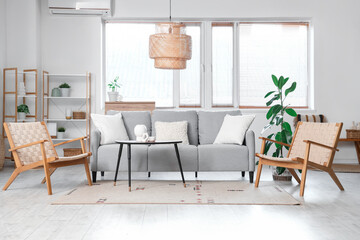 Interior of stylish living room with cozy wooden armchairs, modern grey sofa and coffee table