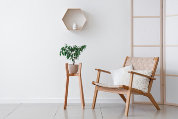 Interior of stylish living room with cozy wooden armchair, folding screen and houseplant