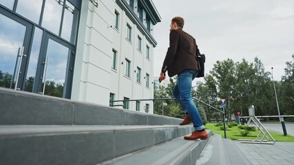 Man walking up steps to modern office building in urban setting