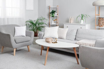 Interior of stylish living room with cozy grey armchairs, sofa and coffee table