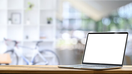 Laptop with a blank screen on wooden desk in a bright stylish office