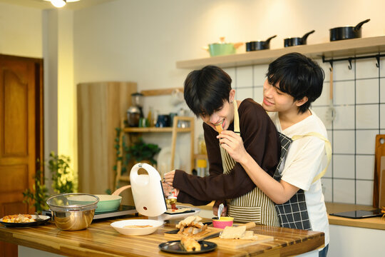 Joyful gay couple sharing a lighthearted moment in the kitchen while preparing food together.