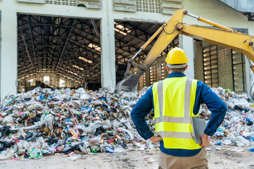 Recycling industry engineer monitoring loader machine performance on a laptop, surrounded by stacks...