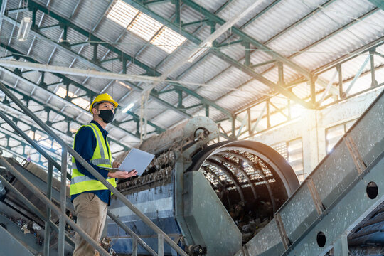 An Engineer working on a laptop surrounded by industrial recycling machines, analyzing data and optimizing processes in waste separation plant. - Powered by Adobe